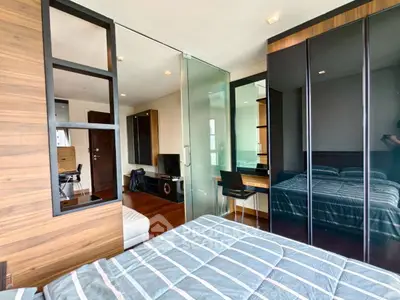 Modern bedroom with glass partition and stylish decor in urban apartment.