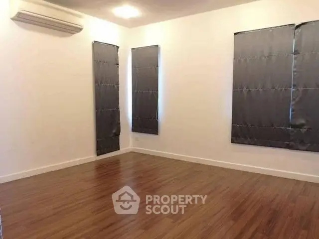 Spacious empty room with wooden flooring and air conditioning, perfect for customization.