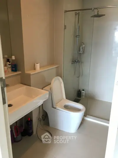 Modern bathroom with glass shower and sleek fixtures in contemporary apartment.