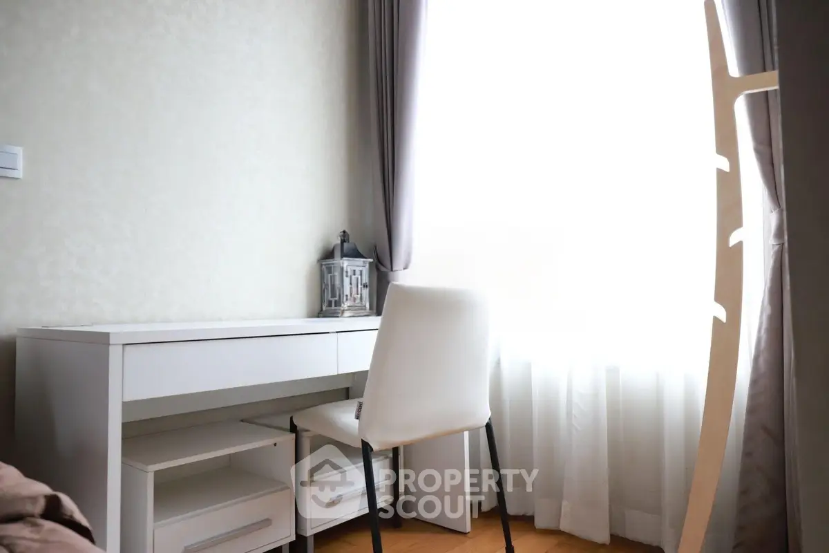 Bright study area with modern white desk and chair by a large window, perfect for productivity.