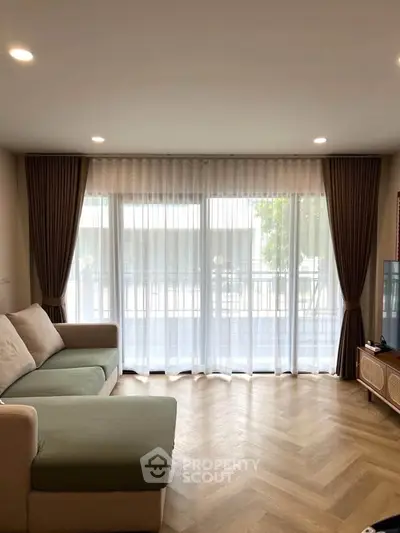 Spacious living room with large windows and elegant curtains, perfect for natural light lovers.