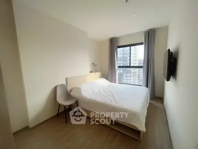 Modern bedroom with large window and minimalist decor in urban apartment.