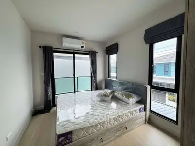 Modern bedroom with large windows and natural light, featuring a comfortable bed and stylish decor.