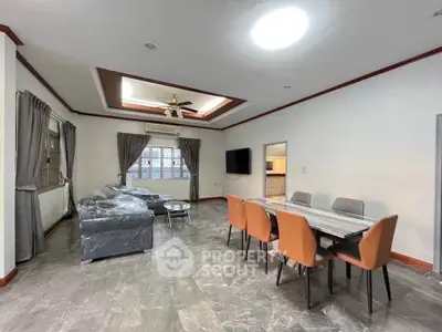Spacious living room with modern dining area and stylish ceiling design.