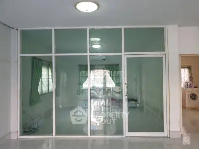 Spacious interior with glass partition and natural light, ideal for versatile living space.
