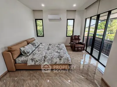Spacious bedroom with modern decor and large windows offering natural light and garden view.