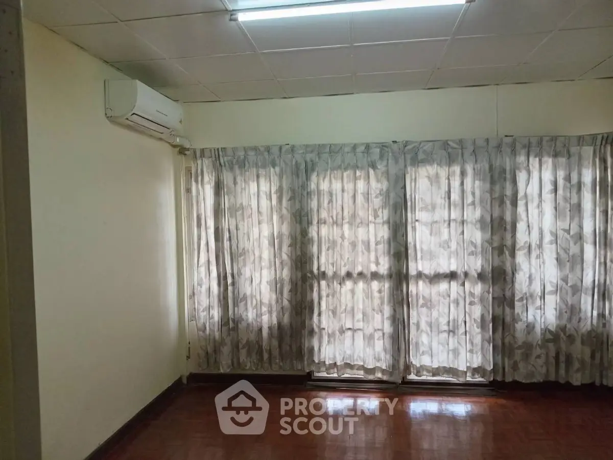 Spacious room with large windows and air conditioning, perfect for natural light and comfort.