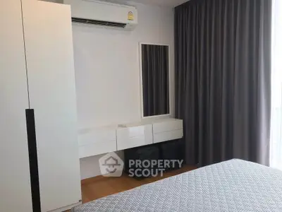 Modern bedroom with sleek furniture and air conditioning, featuring elegant curtains and a stylish mirror.