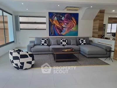 Modern living room with stylish gray sectional sofa and abstract art on the wall