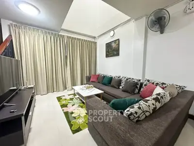 Cozy living room with sectional sofa, floral rug, and wall art, perfect for relaxation and entertainment.
