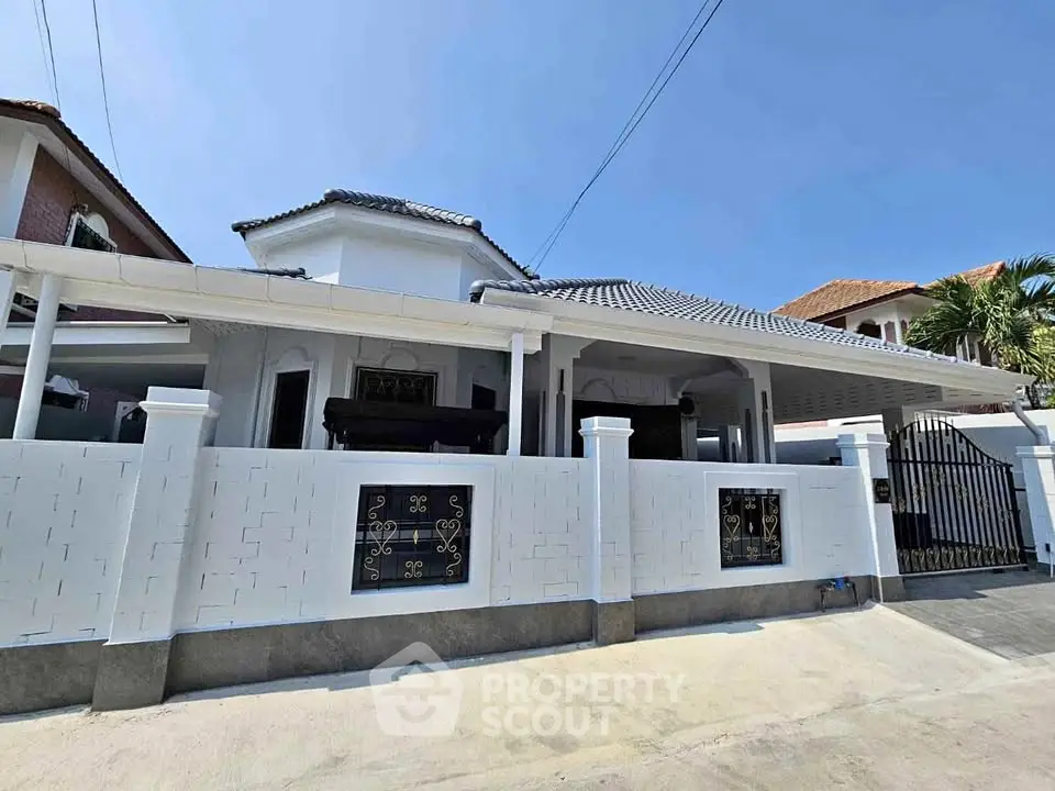Charming white single-story house with tiled roof and gated entrance in a serene neighborhood.