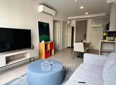 Modern living room with sleek furniture and open kitchen layout in a stylish apartment.