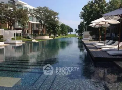 Luxurious poolside view with modern loungers and lush greenery in upscale residential complex.