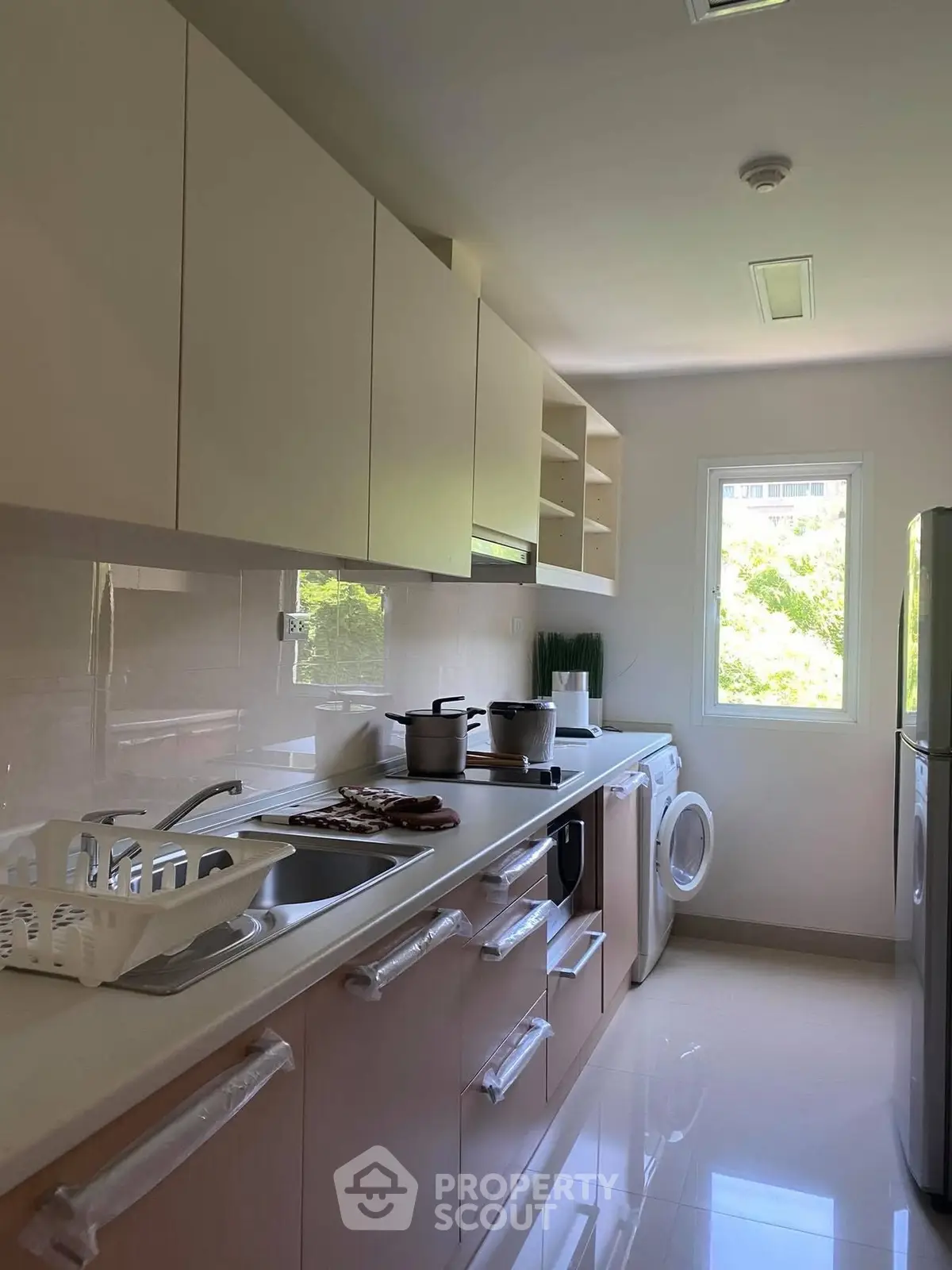Modern kitchen with sleek cabinetry, washing machine, and bright window view.