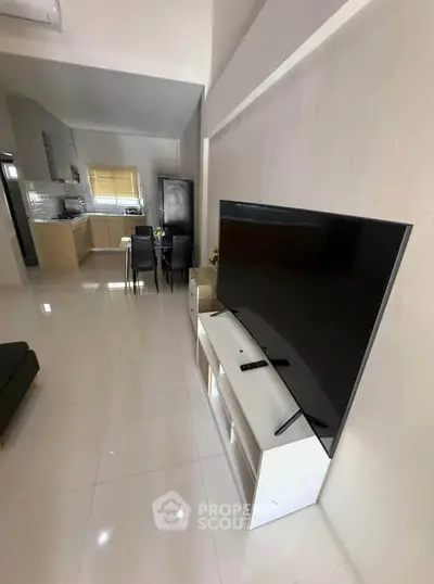 Modern open-plan living room with sleek kitchen and large TV setup.