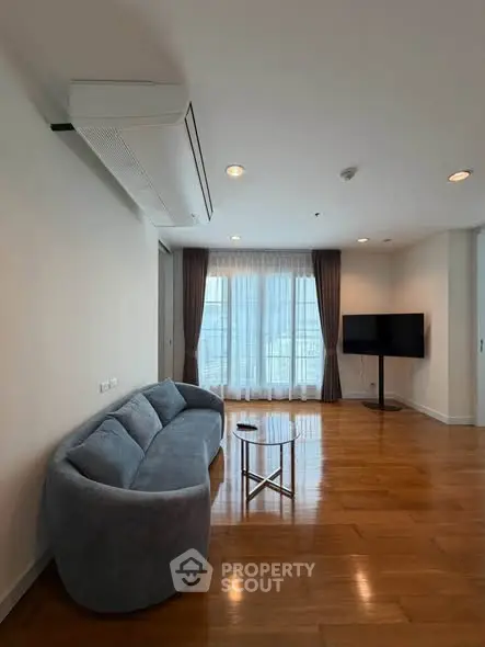 Spacious living room with modern sofa and large windows offering natural light.