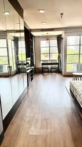 Spacious living room with large windows and modern decor, offering abundant natural light and city views.