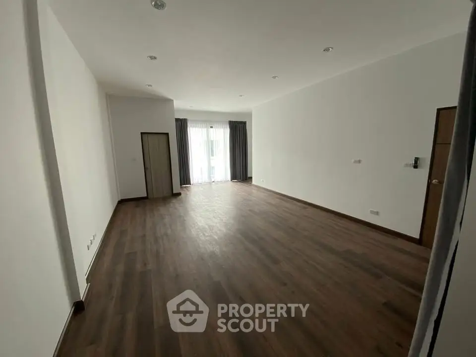 Spacious empty living room with wooden flooring and large windows
