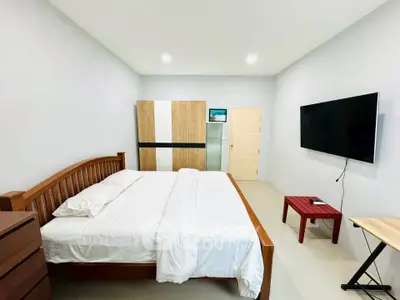 Spacious bedroom with modern furnishings and wall-mounted TV in a stylish apartment.