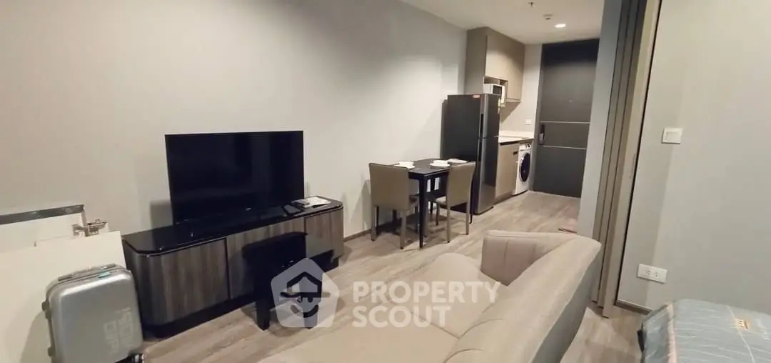 Modern open-plan living room with sleek furniture and kitchen area in a stylish apartment.