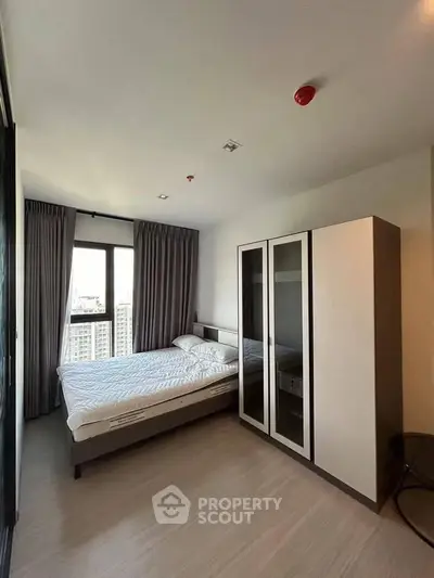 Modern bedroom with large window and sleek wardrobe in high-rise apartment