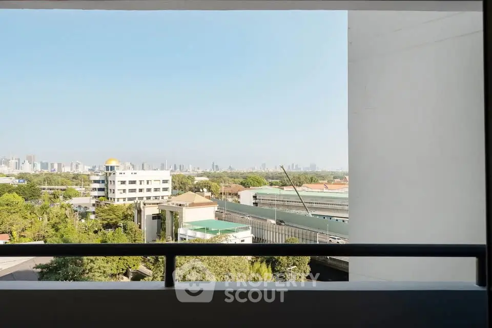 Stunning cityscape view from a high-rise balcony, showcasing urban skyline and lush greenery.