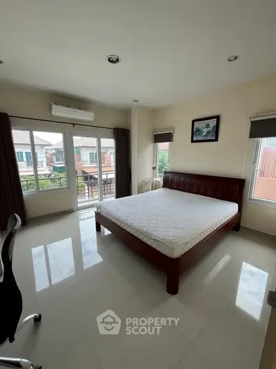 Spacious bedroom with large windows and modern furnishings in a bright, airy setting.