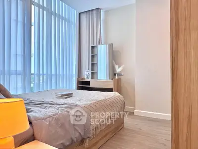 Modern bedroom with large windows and stylish decor, featuring a cozy bed and elegant furnishings.