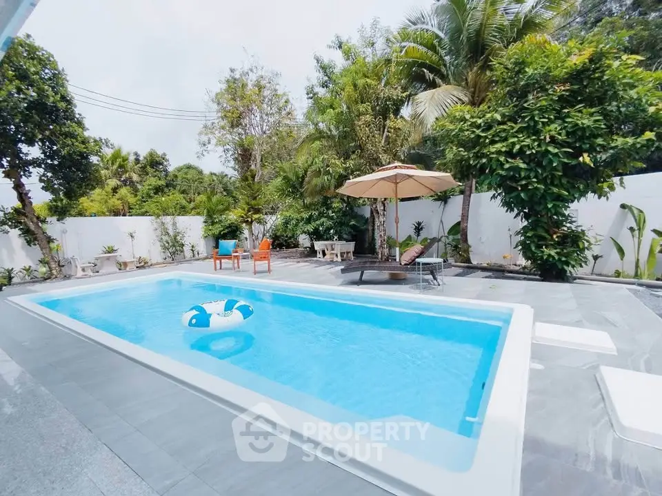 Luxurious outdoor pool area with lush greenery and modern patio furniture, perfect for relaxation.