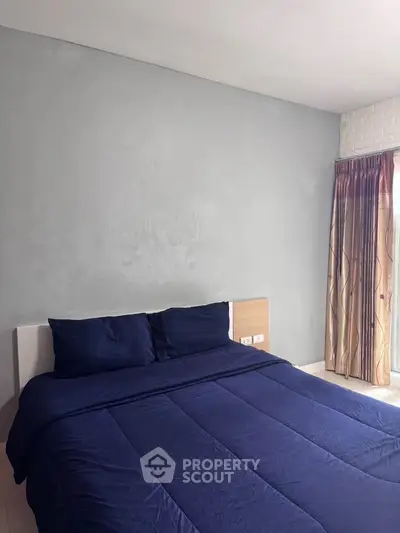 Cozy bedroom with blue bedding and natural light from window
