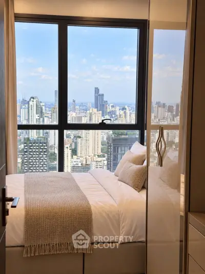 Luxurious bedroom with stunning city view from high-rise apartment window.