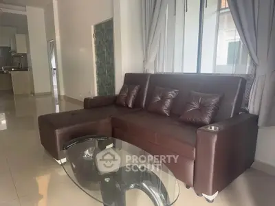 Modern living room with brown leather sofa and glass coffee table in a spacious open layout.
