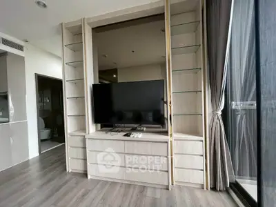 Modern living room with sleek TV unit and large windows offering natural light.