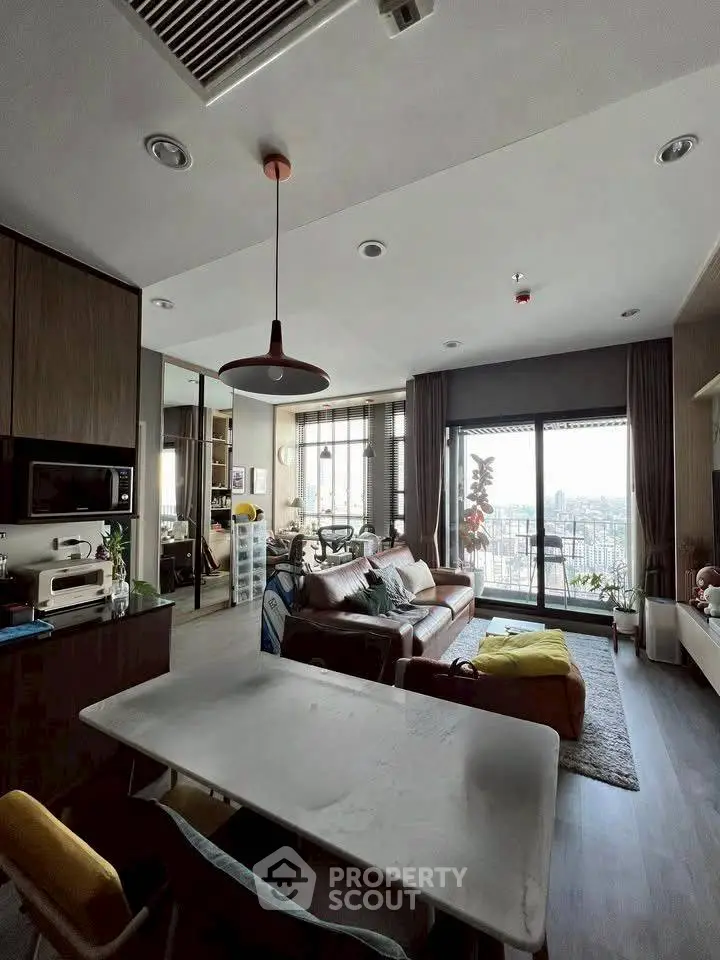 Modern living room with city view, stylish furniture, and open layout in a high-rise apartment.