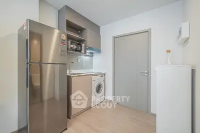 Modern kitchen with stainless steel fridge and washing machine in compact layout.