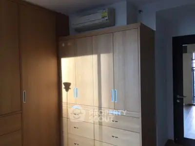 Spacious bedroom with built-in wooden wardrobes and air conditioning unit.