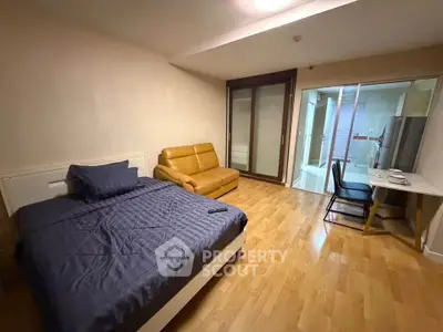 Modern studio apartment with cozy bed, sofa, and dining area, featuring sleek wooden flooring and glass partition.