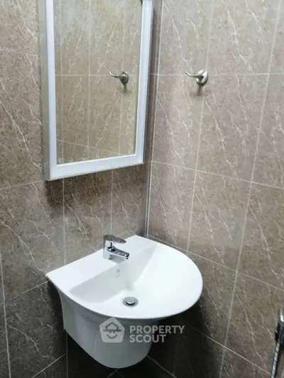 Compact bathroom with modern sink and mirror, featuring elegant tile design.
