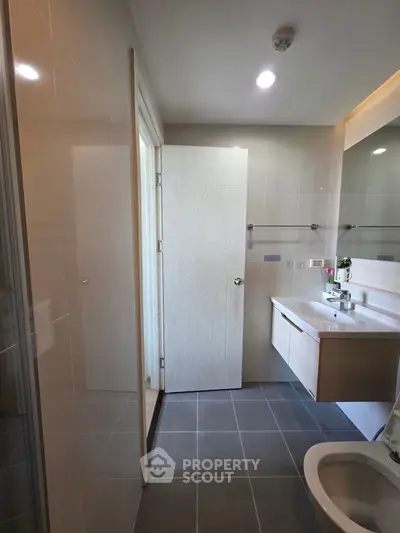 Modern bathroom with sleek fixtures and ample lighting, featuring a spacious shower and elegant vanity.