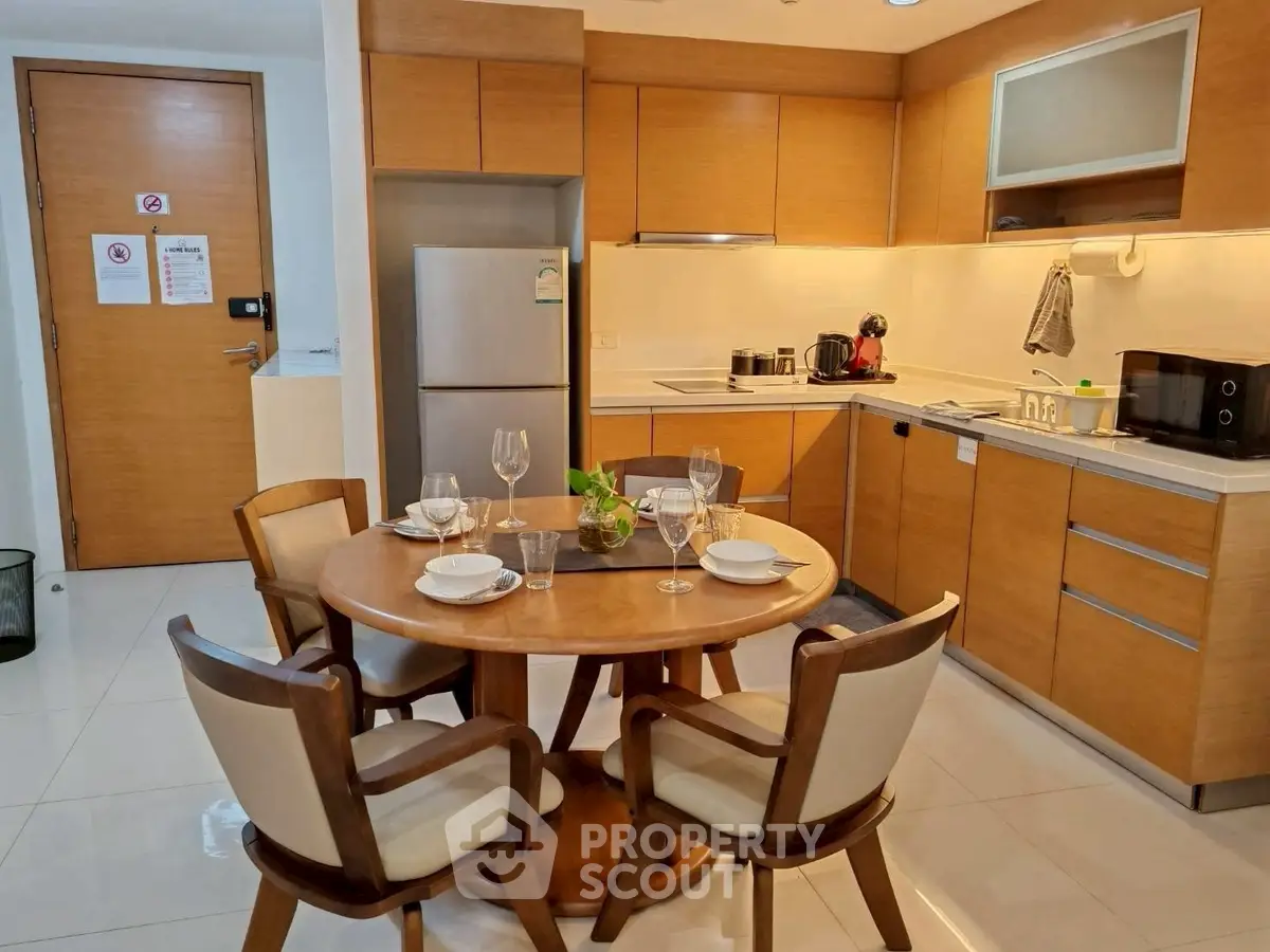 Modern kitchen with wooden cabinets and dining area in cozy apartment.