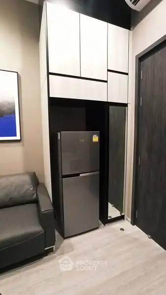 Modern compact kitchen with sleek cabinetry and stainless steel fridge
