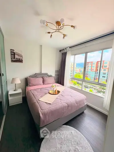 Charming bedroom with large window offering cityscape views, featuring elegant decor and cozy ambiance.