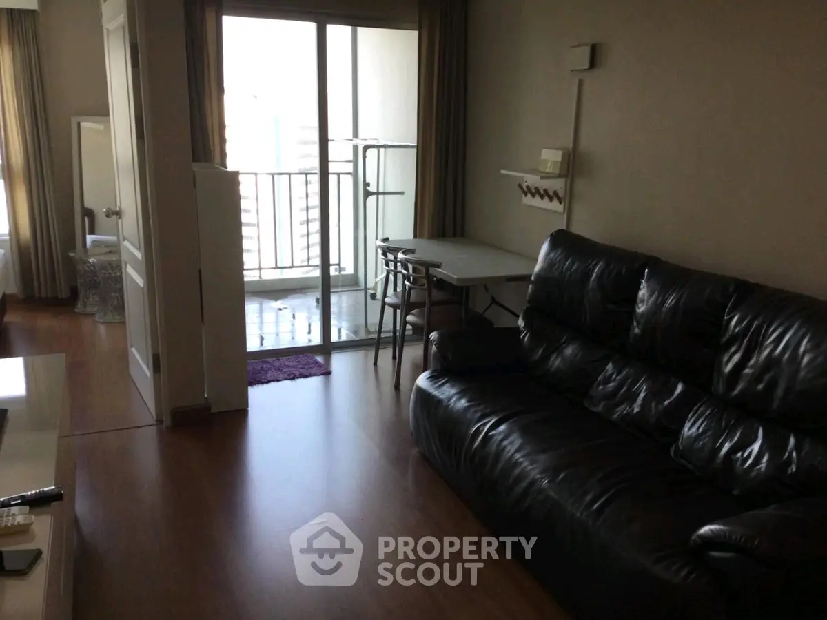 Spacious living room with leather sofa and balcony access in modern apartment.