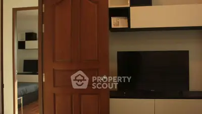 Modern living room with sleek TV unit and wooden door, showcasing contemporary interior design.