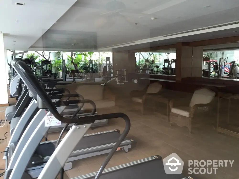 Modern gym with state-of-the-art equipment and mirrored walls in luxury residential building.