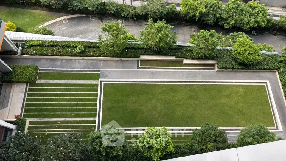 Aerial view of a modern landscaped garden with lush greenery and paved pathways in a residential complex.