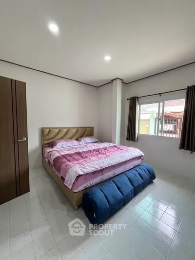 Cozy bedroom with large bed and window view, perfect for relaxation.