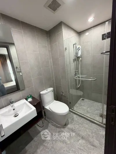 Modern bathroom with glass shower and sleek fixtures in contemporary apartment.
