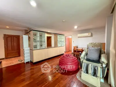 Spacious living room with wooden flooring and modern furnishings in a cozy apartment.