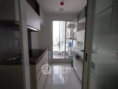 Modern kitchen with sleek cabinetry and balcony access in a stylish apartment.